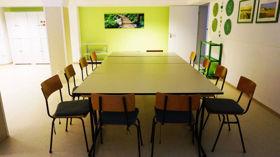 GH_Raum2 Blick in den Saal im Untergeschoss Gemeindezentrum mit Tisch und Stühlen