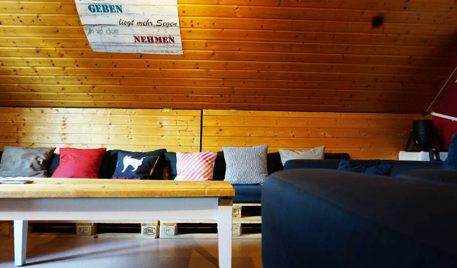 Gemeinde-leben-Jugend-GH_Jugendraum-scaled Innenansicht Jugendraum im Gemeindezentrum mit blauem Sofa und vielen Kissen