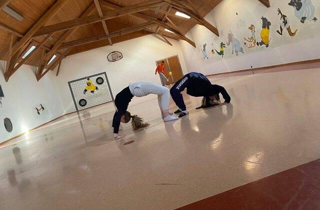 Gemeinde-leben-Jugend-thumbnail_PHOTO-2022-03-17-13-15-27-e1653858505746 Blick in eine Turnhalle mit zwei Teenagermädchen beim Turnen