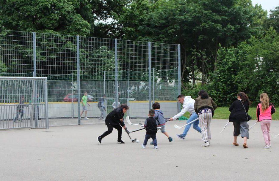 IMG_6883-1 7 Kinder verschiedenen Alters spielen Hockey auf einem Bolzplatz