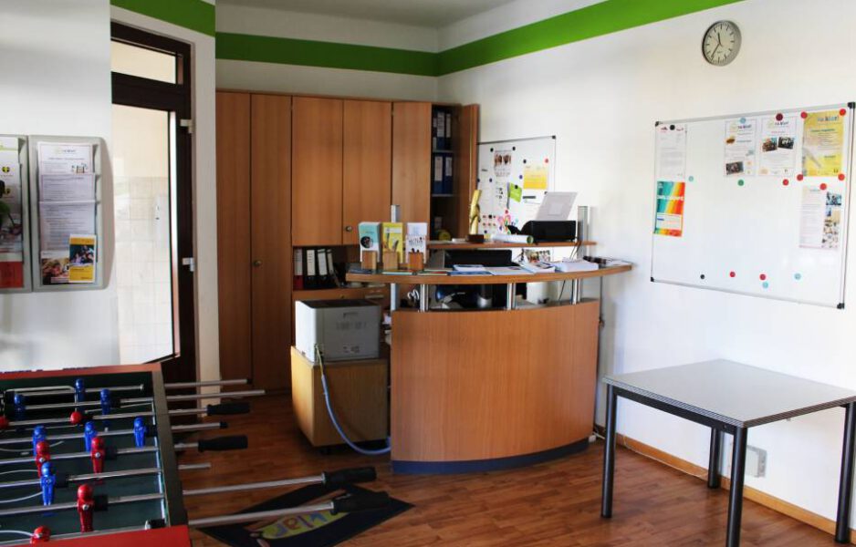 Na-klar_Innen_bearbeitet-scaled Empfangstheke im Nachbarschaftstreff Na Klar mit zwei Pinnwänden und davor ein Kicker