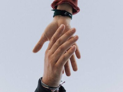 eine Hand von unten fasst eine Hand von oben